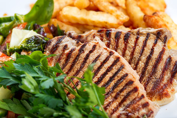 Grilled pork meat  with fried potatoes and vegetables