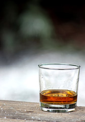 A whiskey glass sitting on a wood table with a blurred background