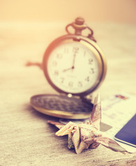 Financial time concept. Origami crane or bird made from a money note with watch time in out of focus background. Vintage style and filtered process.