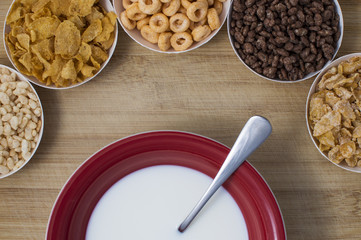 Corn flakes in small plates and plate of milk on wooden board