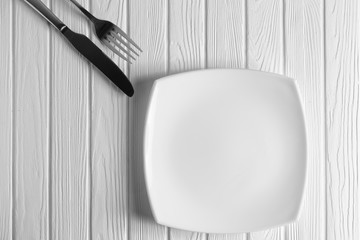 Empty plate, fork and knife on wood background