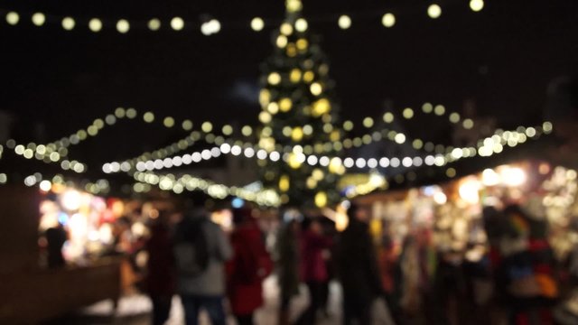 People visit Christmas Fair in old town at evening. Blurred