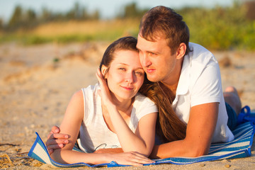 Young beautiful couple in love relax lying on the beach