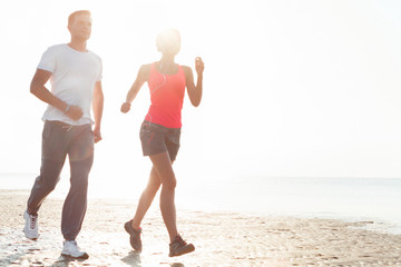 Young couple running together beside the water at the beach. Man