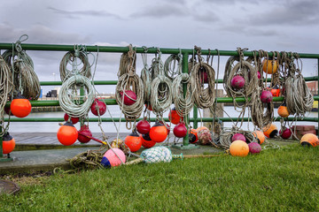Landscape of a harbor with fisherman's equipment with orange buoy, rope and nets hanging over a gate