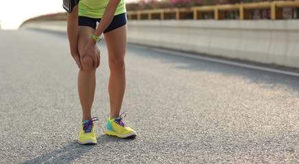 woman runner hold her injured leg on road