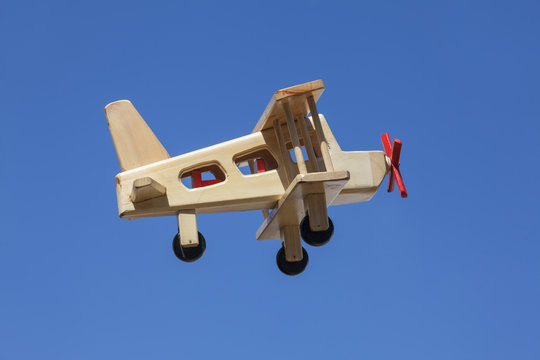 Avión de madera volando con cielo azul - Vista lateral