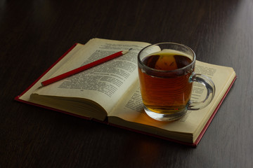 Cup of tea on table with book and pencil