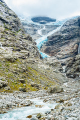 Norwegian glacier between rocky mountains with small glacial str