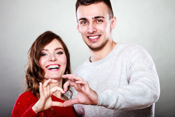 Young couple making heart shape by hands
