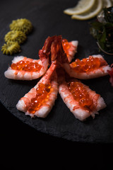 SASHIMI with shrimps and red caviar, sushi on a black background, Japanese cuisine