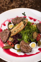 Salad with meat, lettuce, quail eggs, pickled cucumbers, red pepper sauce