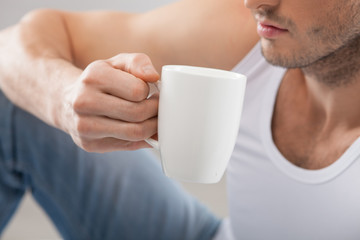 Cheerful young guy is drinking hot tea