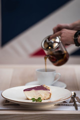 Cake is on a plate, and in the background is poured tea