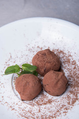 Three candies with chocolate chips lie on a plate decorated with mint leaves