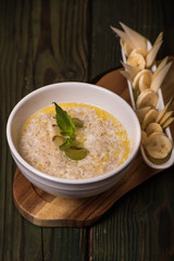 Oatmeal with milk in a bowl and next to sliced banana