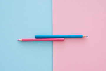blue and pink pencils on pink and blue paper background