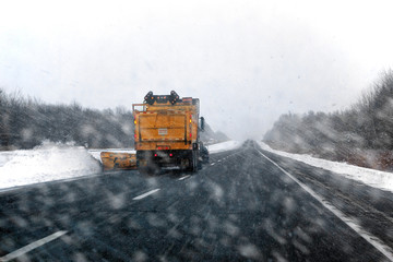 Snowplow clearing snow on a highway during a snowstorm