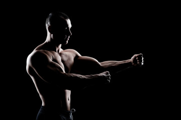 Obraz na płótnie Canvas bodybuilder demonstrates biceps on a dark background