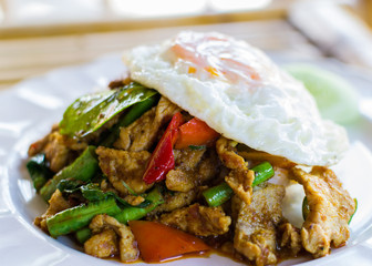 Stir fried pork with curry paste serve with fried egg