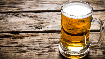 Glass of light beer on wooden table.