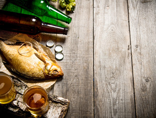 Smoked fish and fresh beer on a wooden table. Free space for text.