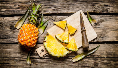 Sliced fresh pineapple with a knife on a chopping Board.
