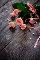 Beautiful pink roses on a dark wooden table, with space for text