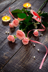 Beautiful pink roses and candle on a dark wooden table