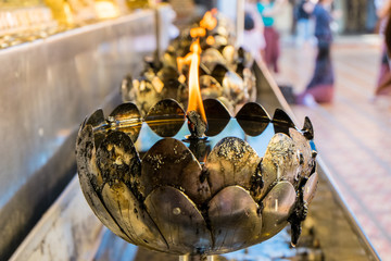 Oil filling in Thai style metal candle in Doi Suthep temple, Chiang Mai, Thailand. Selective focus with blurred background