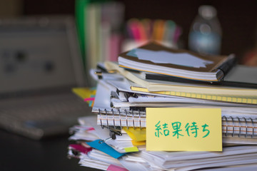 Waiting Result; Stack of Documents and Laptop at working Desk.