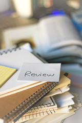 Review; Stack of Documents and Laptop at working Desk.