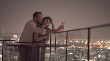 Young couple taking selfie photo on rooftop terrace at night - Powered by Adobe