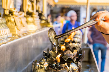 Oil filling in Thai style metal candle in Doi Suthep temple, Chiang Mai, Thailand. Selective focus with blurred background