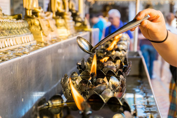 Oil filling in Thai style metal candle in Doi Suthep temple, Chiang Mai, Thailand. Selective focus with blurred background
