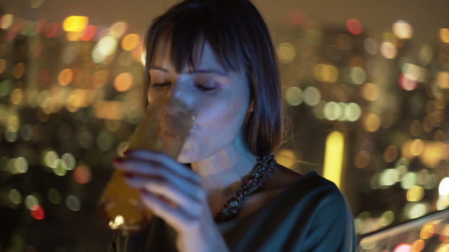Young woman relaxing and drinking cocktail in bar at night

