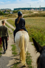 closeup of a back view of a young woman on horseback at the coun