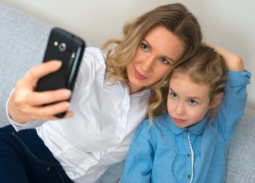Mother and daughter taking selfie with mobile phone.