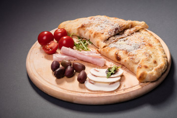 Calzone folded pizza served on wooden plate