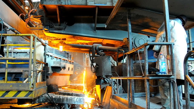 molten metal poured from ladle into mold at steel plant