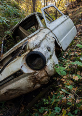 old broken car in a forest ravine lies