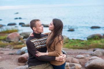 young couple sitting on a boulder on the beach