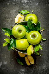 Fototapeta na wymiar Green apples with leaves in the bucket.