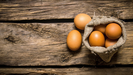 Eggs with an old bag. On wooden table.