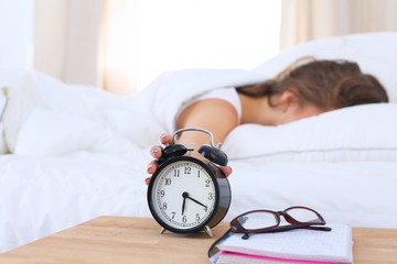 A young woman putting her alarm clock off in the morning