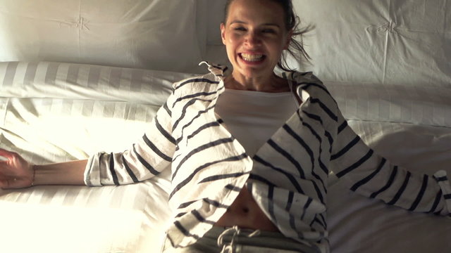 Young, happy woman falling on bed in room, super slow motion 240fps
