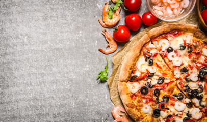 Seafood pizza with shrimp and tomatoes. On stone table.