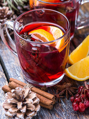 Hot drink, mulled wine red in a cup of glass on a wooden background