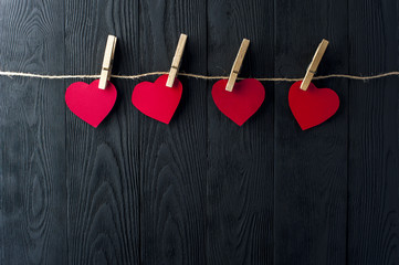 Red hearts with clothespins on dark background