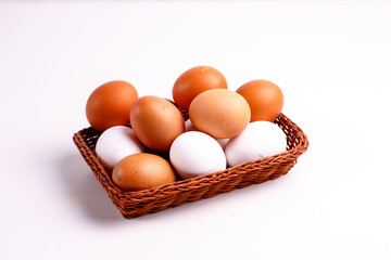 Brown and white chicken eggs lying in a wicker basket.